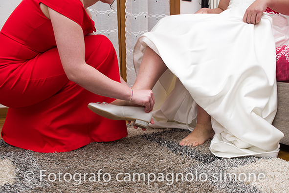 fotografo matrimonio Marostica, servizio fotografico sposi Marostica, foto nozze Marostica, album sposi Marostica, jari e lara, sposi a Marostica, calzature sposa, scarpe da sposa a Marostica, la testimone di nozze aiuta la sposa a mettere le scarpe a Marostica, foto vestizione a casa della sposa a Marostica