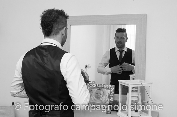 fotografo matrimonio Marostica, servizio fotografico sposi Marostica, foto nozze Marostica, album sposi Marostica, jari e lara, sposi a Marostica, foto in biano e nero dello sposo mentre si veste a Marostica, si guarda allo specchio e si aggiusta la cravatta