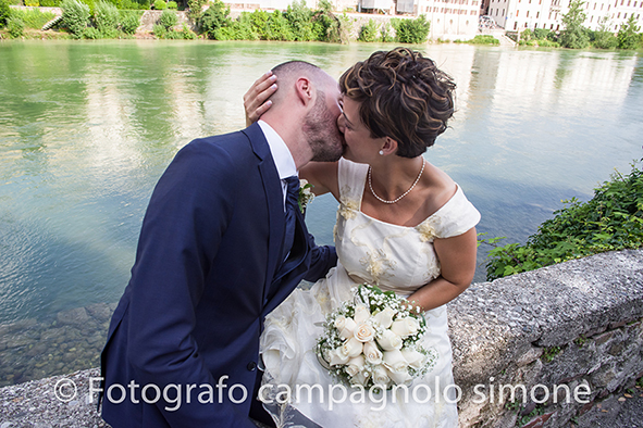 Fotografo matrimoni Rosà, fotografia matrimonio Bassano del grappa, servizio fotografico matrimoniale a Rosà e Bassano del Grappa,, fotografo sposi Rosà e Bassano del grappa, la sposa sostiene la testa dello sposo e lo bacia appassionatamente lungo le rive del fiume brenta.