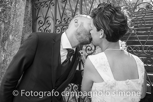 Fotografo matrimoni Rosà, fotografia matrimonio Bassano del grappa, servizio fotografico matrimoniale a Rosà e Bassano del Grappa,, fotografo sposi Rosà e Bassano del grappa, accanto a un portone, lo sposo bacia la sposa dopo il matrimonio a Rosà