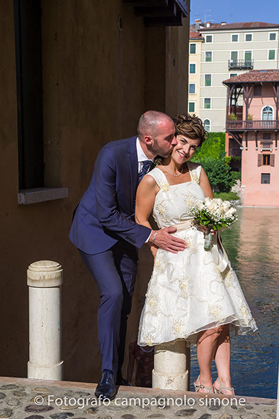 Fotografo matrimoni Rosà, fotografia matrimonio Bassano del grappa, servizio fotografico matrimoniale a Rosà e Bassano del Grappa,, fotografo sposi Rosà e Bassano del grappa, sotto il ponte, lo sposo bacia sulla guancia la moglie.