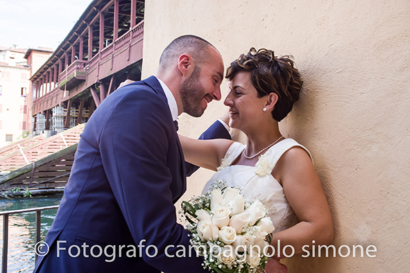 Fotografo matrimoni Rosà, fotografia matrimonio Bassano del grappa, servizio fotografico matrimoniale a Rosà e Bassano del Grappa,, fotografo sposi Rosà e Bassano del grappa, gli sposi ridono mentre si guardano, sullo sfondo il ponte degli alpini