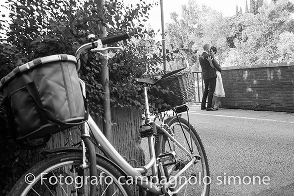 Fotografo matrimoni Rosà, fotografia matrimonio Bassano del grappa, servizio fotografico matrimoniale a Rosà e Bassano del Grappa,, fotografo sposi Rosà e Bassano del grappa, gli sposi si baciano in lontananza, la bicicletta è in primo piano