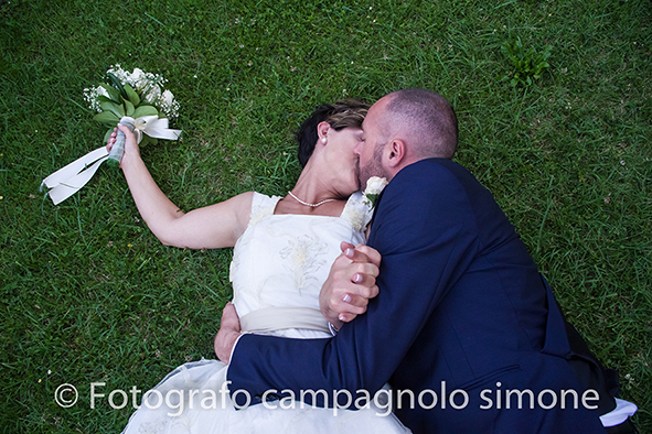 Fotografo matrimoni Rosà, fotografia matrimonio Bassano del grappa, servizio fotografico matrimoniale a Rosà e Bassano del Grappa,, fotografo sposi Rosà e Bassano del grappa, lo sposo bacia la sposa sdraiata sull'erba